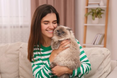 Woman with her cute cat on soft sofa at home