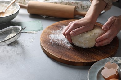 Photo of Woman kneading dough at grey table, closeup