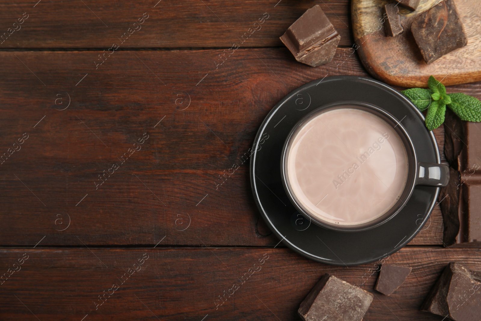 Photo of Cup of delicious hot cocoa, chocolate chunks and fresh mint on wooden table, flat lay. Space for text