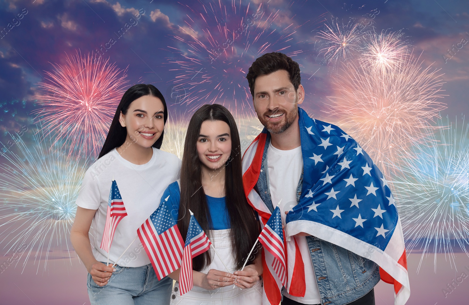 Image of 4th of July - Independence day of America. Happy family with national flags of United States against sky with fireworks