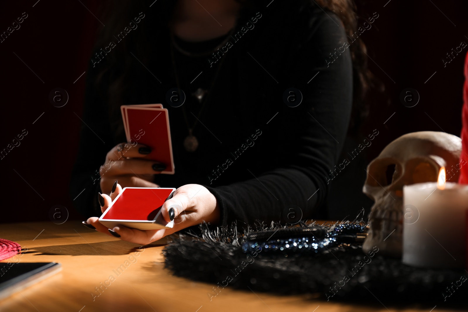 Photo of Soothsayer predicting future with cards at table indoors, closeup