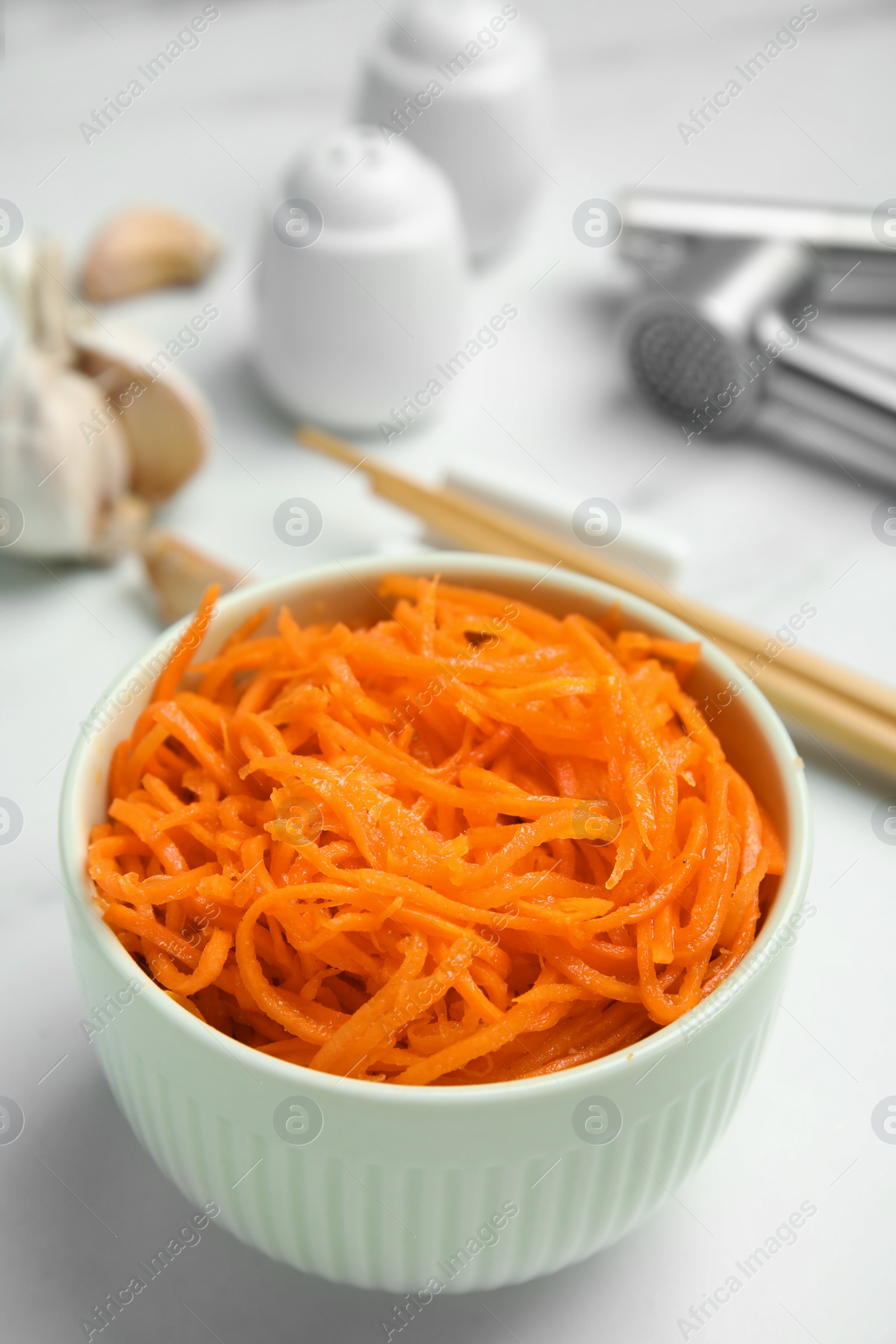 Photo of Delicious Korean carrot salad in bowl on white table