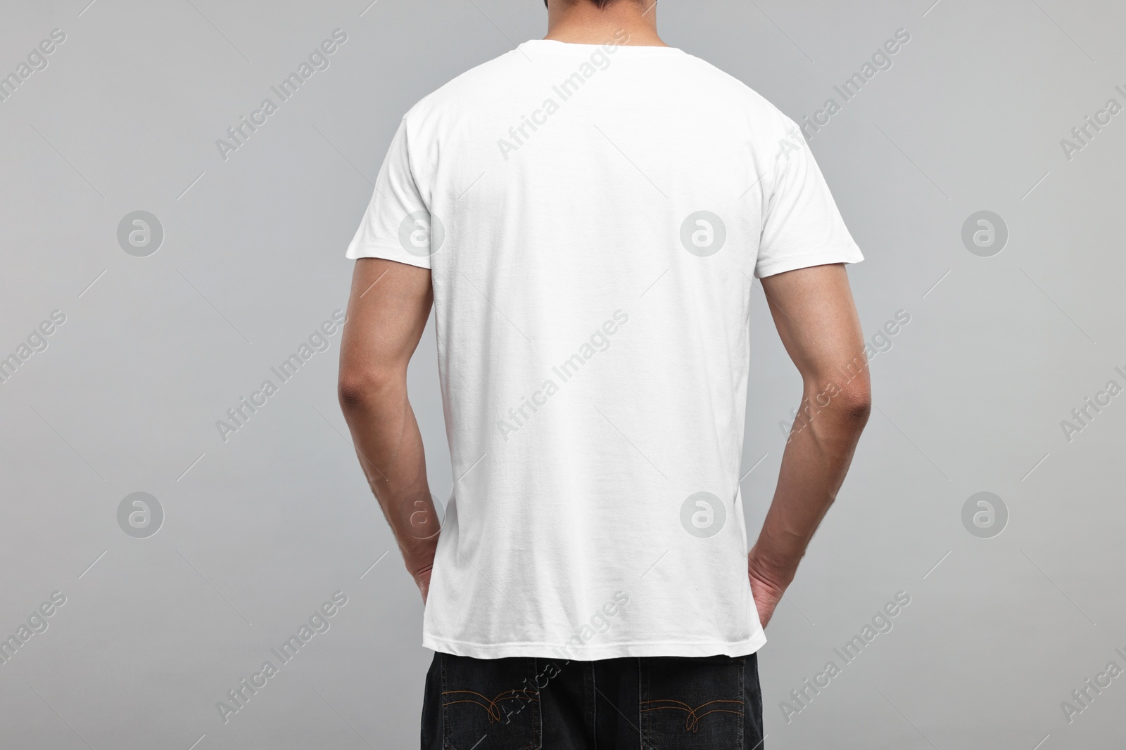Photo of Man in white t-shirt on grey background, back view
