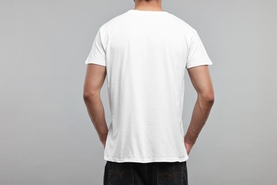 Man in white t-shirt on grey background, back view