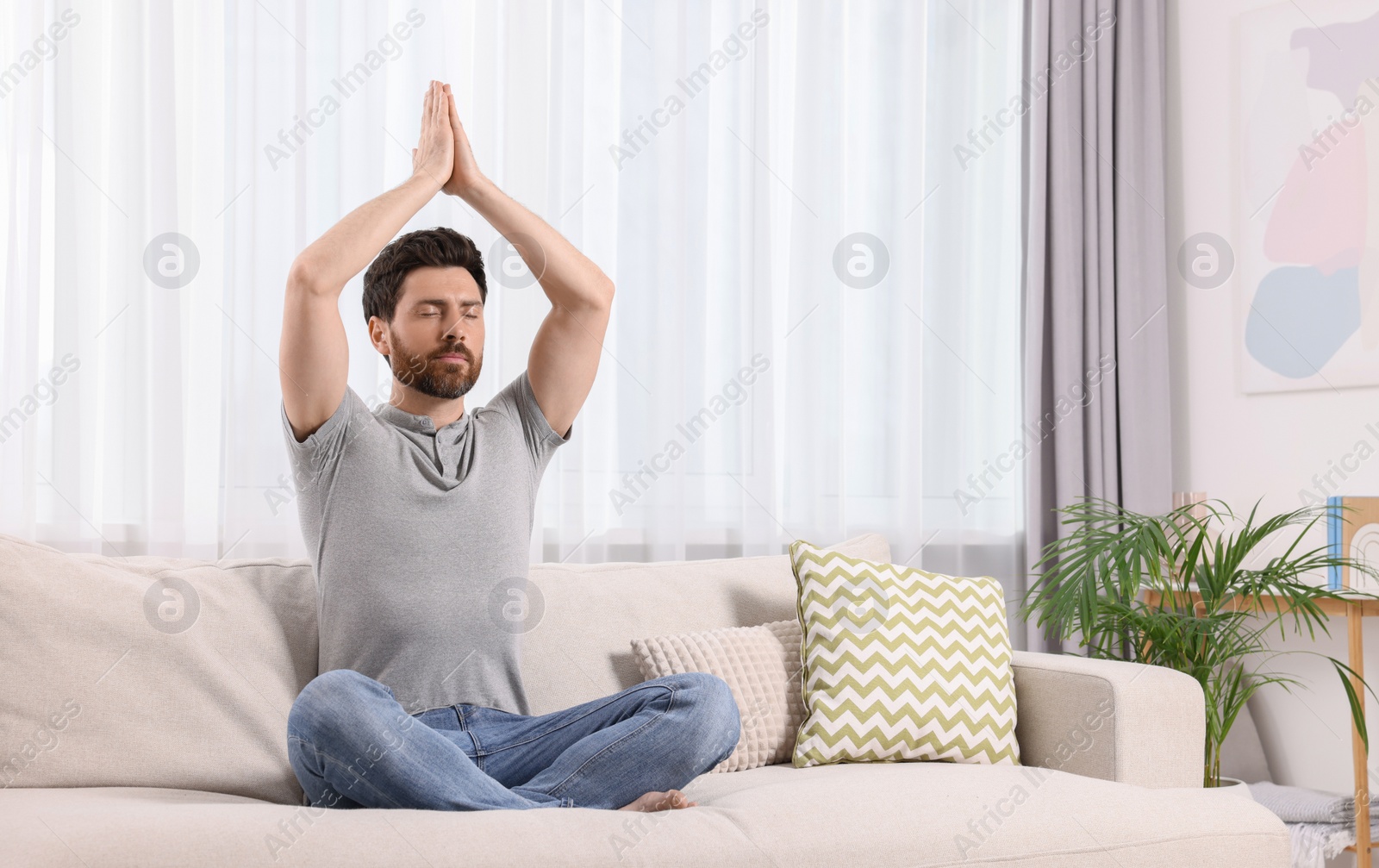 Photo of Man meditating on sofa at home, space for text