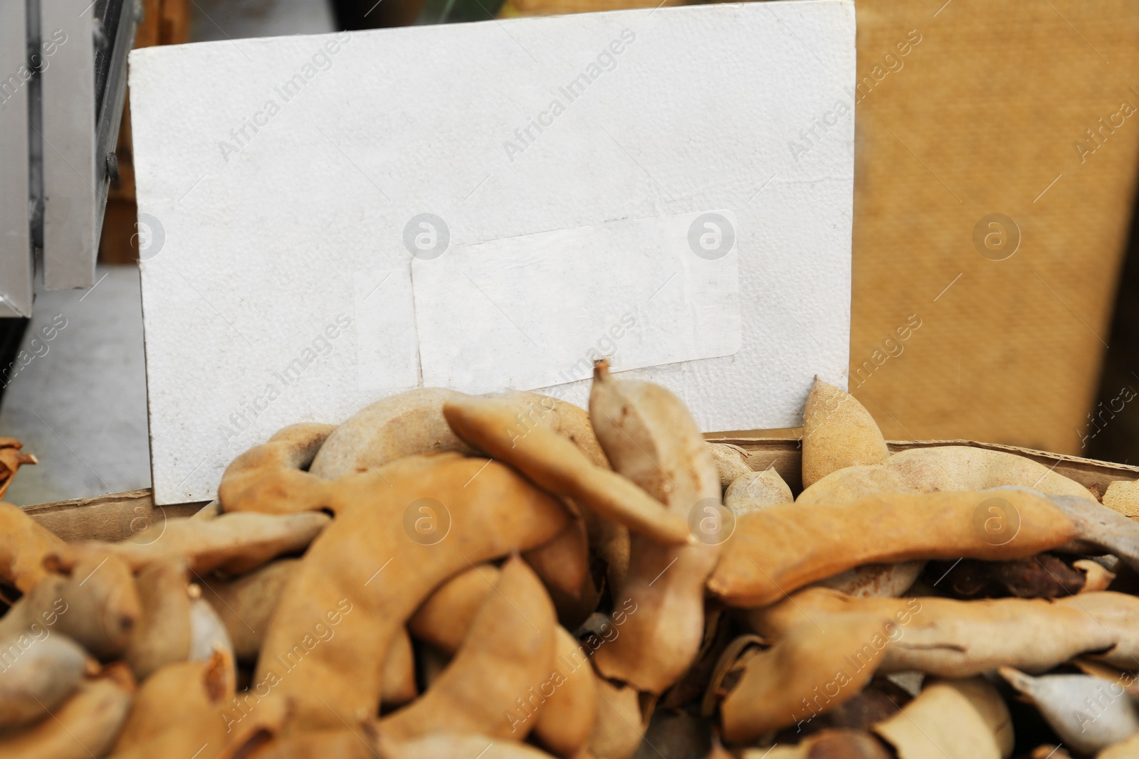 Photo of Pile of ripe tamarind fruits and paper sheet with price at market