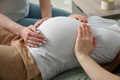 Photo of Doula taking care of pregnant woman indoors, closeup. Preparation for child birth