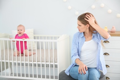 Photo of Young mother suffering from postnatal depression and little baby in room