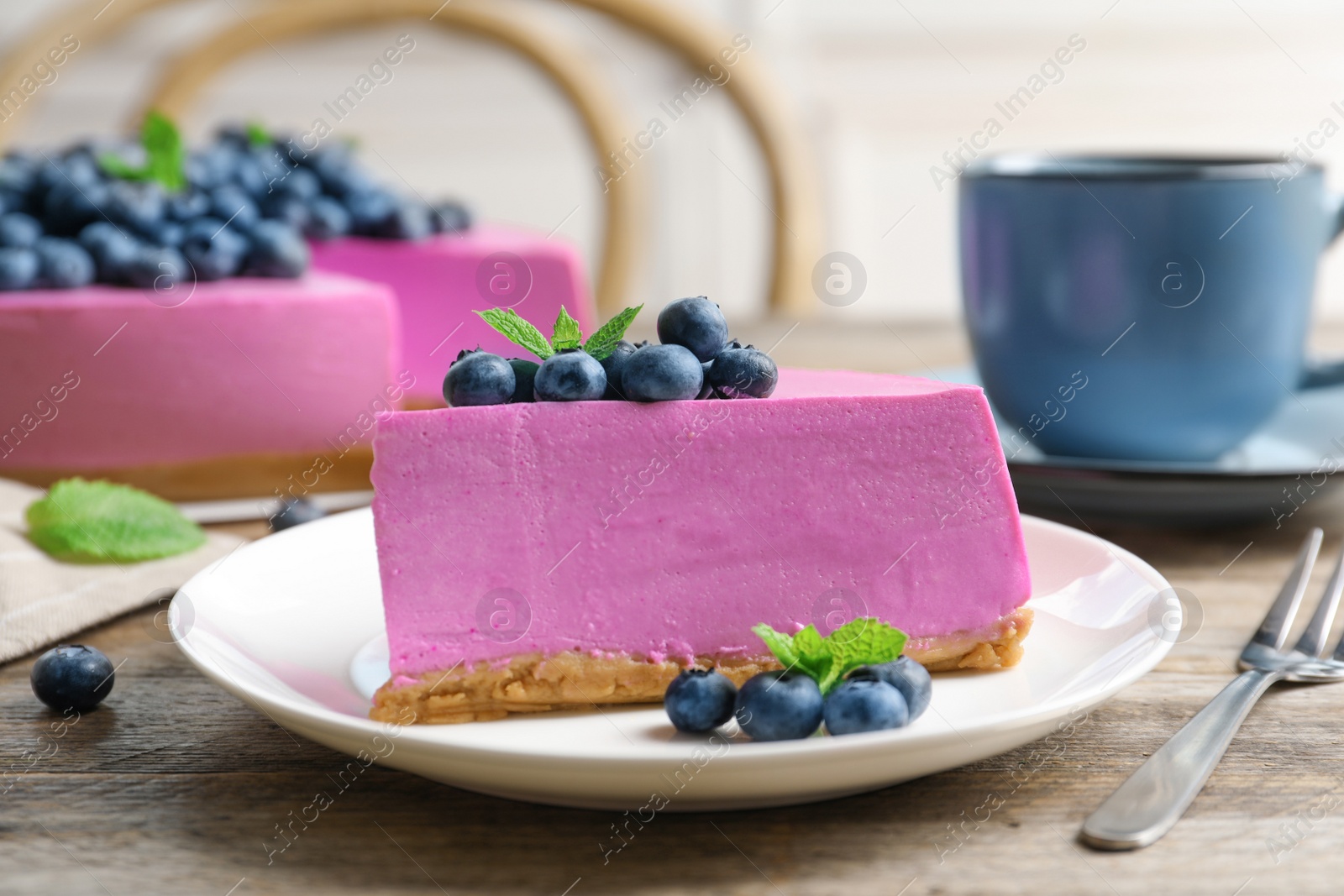 Photo of Plate with piece of tasty blueberry cake on wooden table