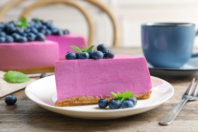 Plate with piece of tasty blueberry cake on wooden table