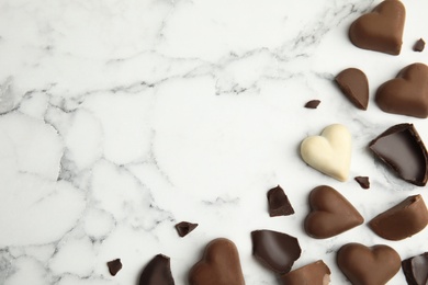 Photo of Tasty heart shaped chocolate candies on white marble table, flat lay with space for text. Happy Valentine's day