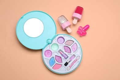 Photo of Children's makeup products and nail polish on pale orange background, flat lay