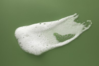 Smudge of white washing foam on olive background, top view