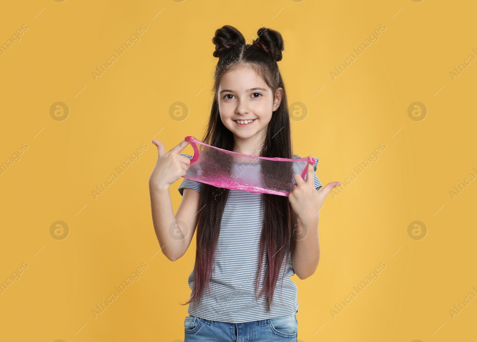 Photo of Little girl with slime on yellow background