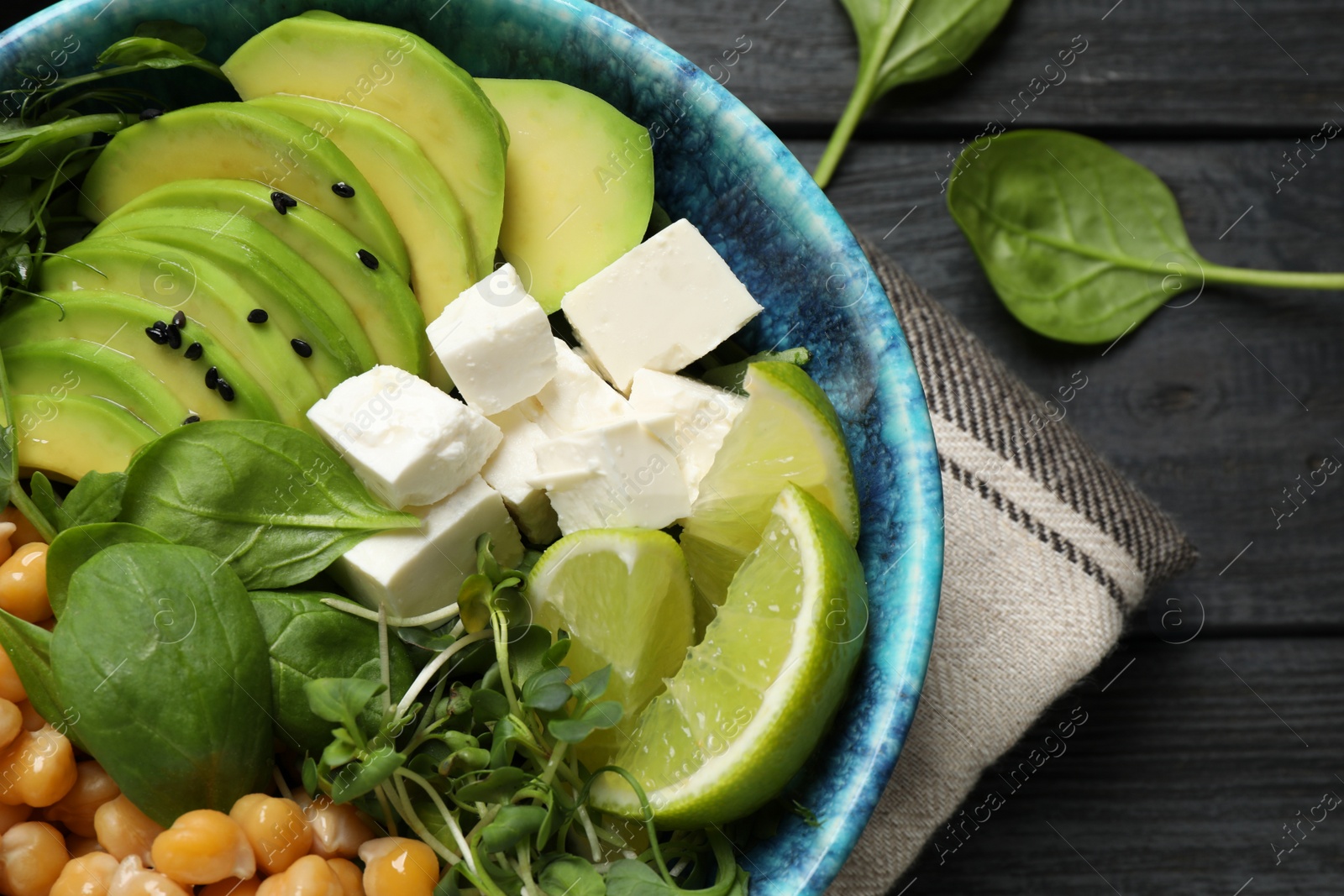 Photo of Delicious avocado salad with chickpea on black wooden table, flat lay