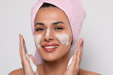 Photo of Beautiful woman applying facial cleansing foam on white background