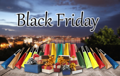 Image of Black Friday. Many gift boxes with shopping bags and blurred cityscape on background