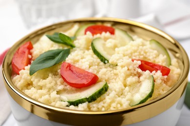 Photo of Tasty couscous with tomatoes, cucumber and basil on table, closeup