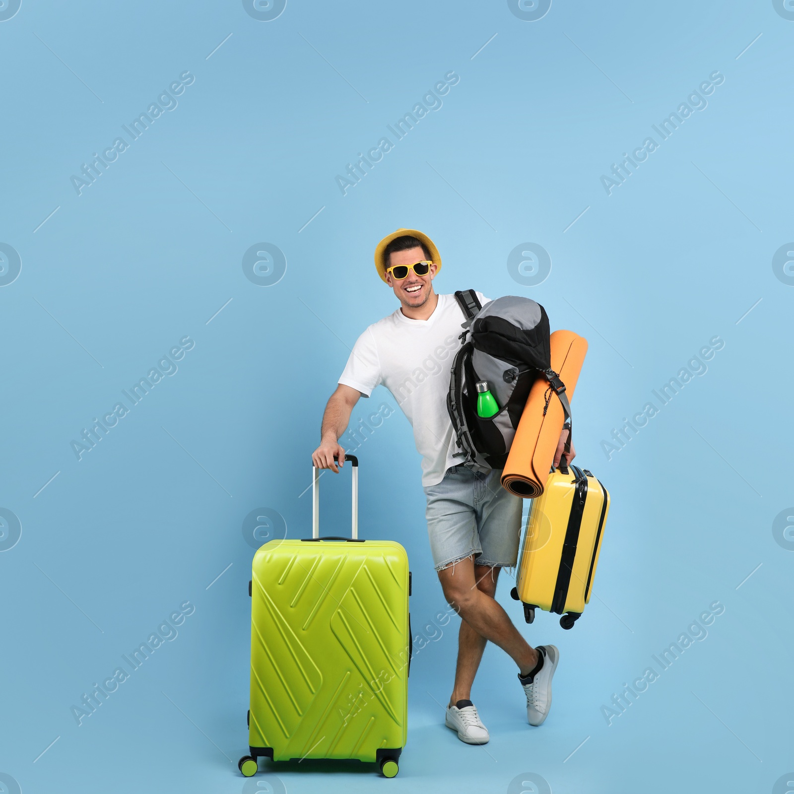 Photo of Male tourist with travel backpack and suitcases on turquoise background