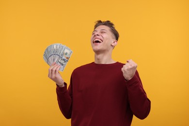 Photo of Happy man with dollar banknotes on yellow background