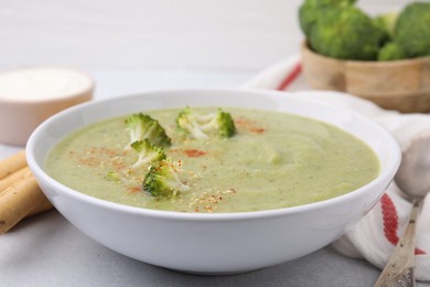 Photo of Delicious broccoli cream soup served on light table, closeup