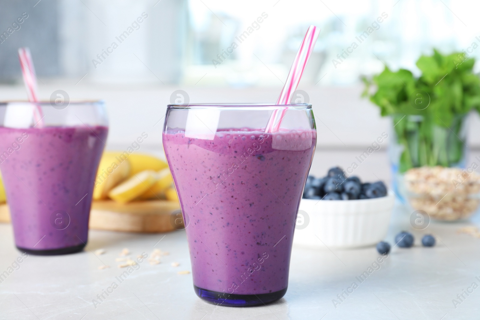 Photo of Glasses of delicious blueberry smoothie served on kitchen table