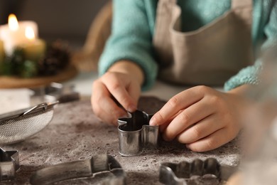 Photo of Little child making Christmas cookies at white table, closeup