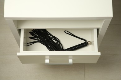 Photo of Black whip in drawer indoors, above view. Sex toy