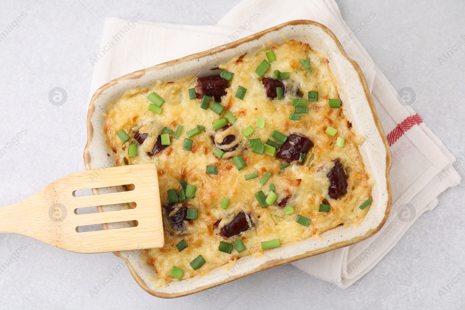 Photo of Tasty sausage casserole with green onions in baking dish on white table, top view