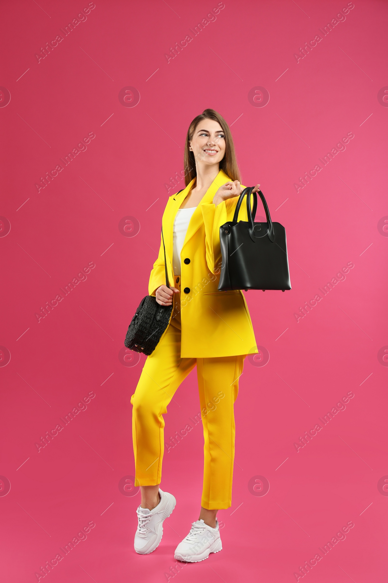 Photo of Beautiful young woman with stylish bags on pink background