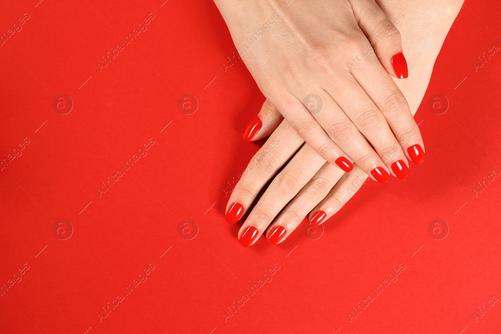Photo of Woman showing manicured hands with red nail polish on color background, top view. Space for text