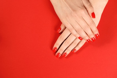 Photo of Woman showing manicured hands with red nail polish on color background, top view. Space for text