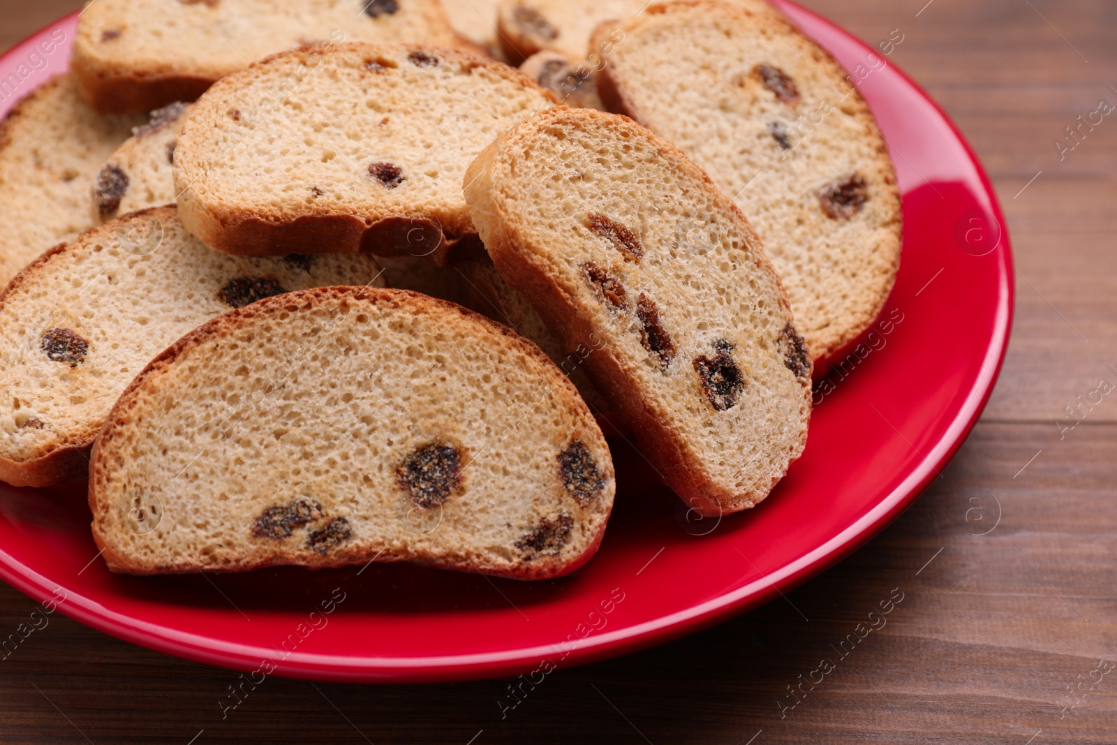 Photo of Plate of sweet hard chuck crackers with raisins on wooden table, closeup