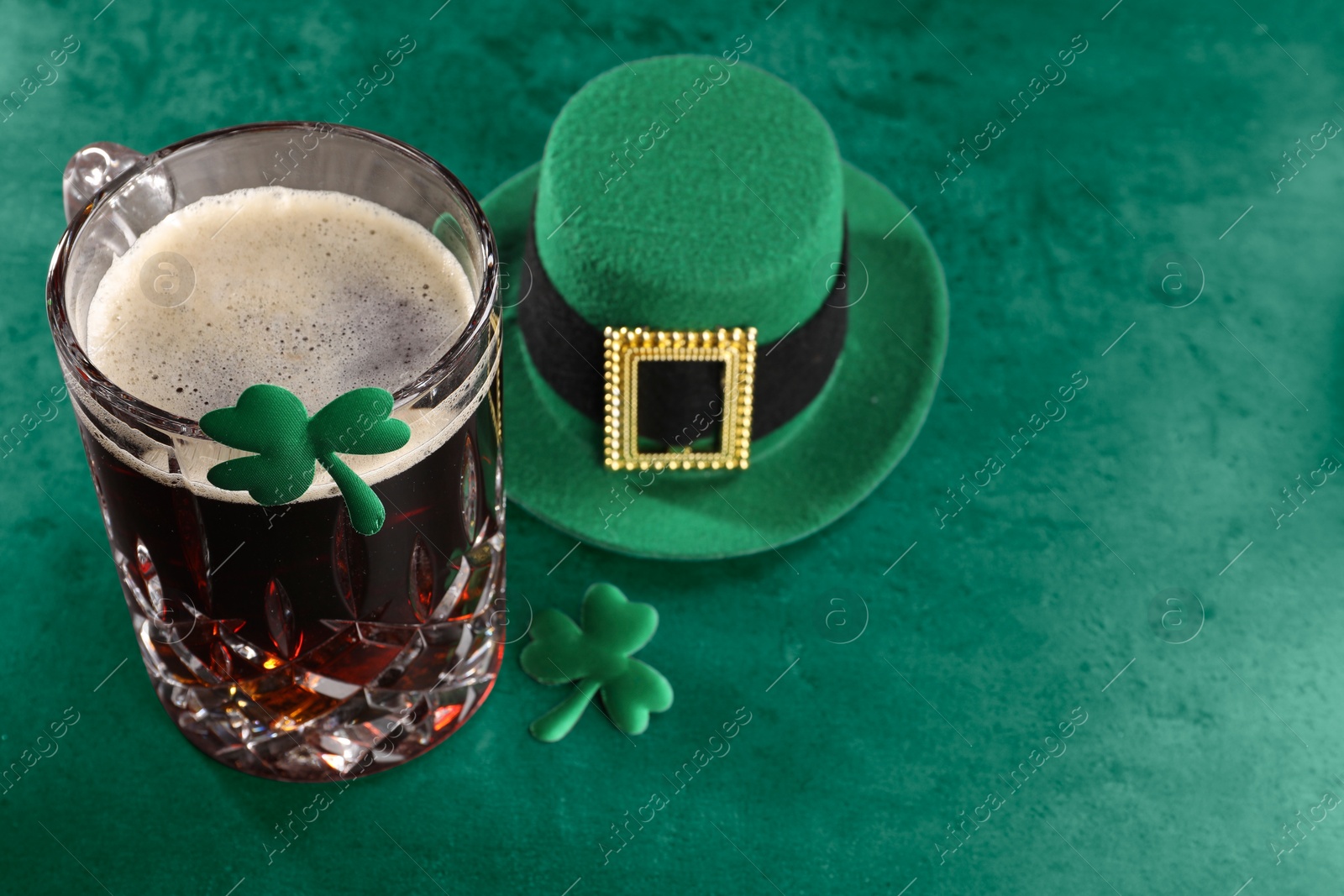 Image of St. Patrick's day. Beer, decorative clover leaves and leprechaun hat on green table, space for text