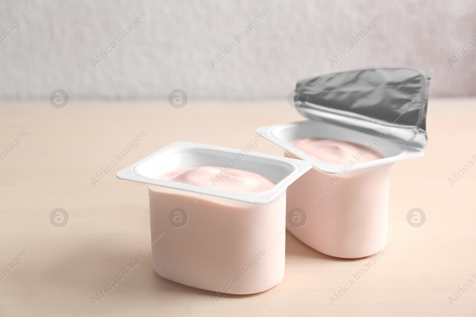 Photo of Plastic cups with yummy yogurt on wooden table