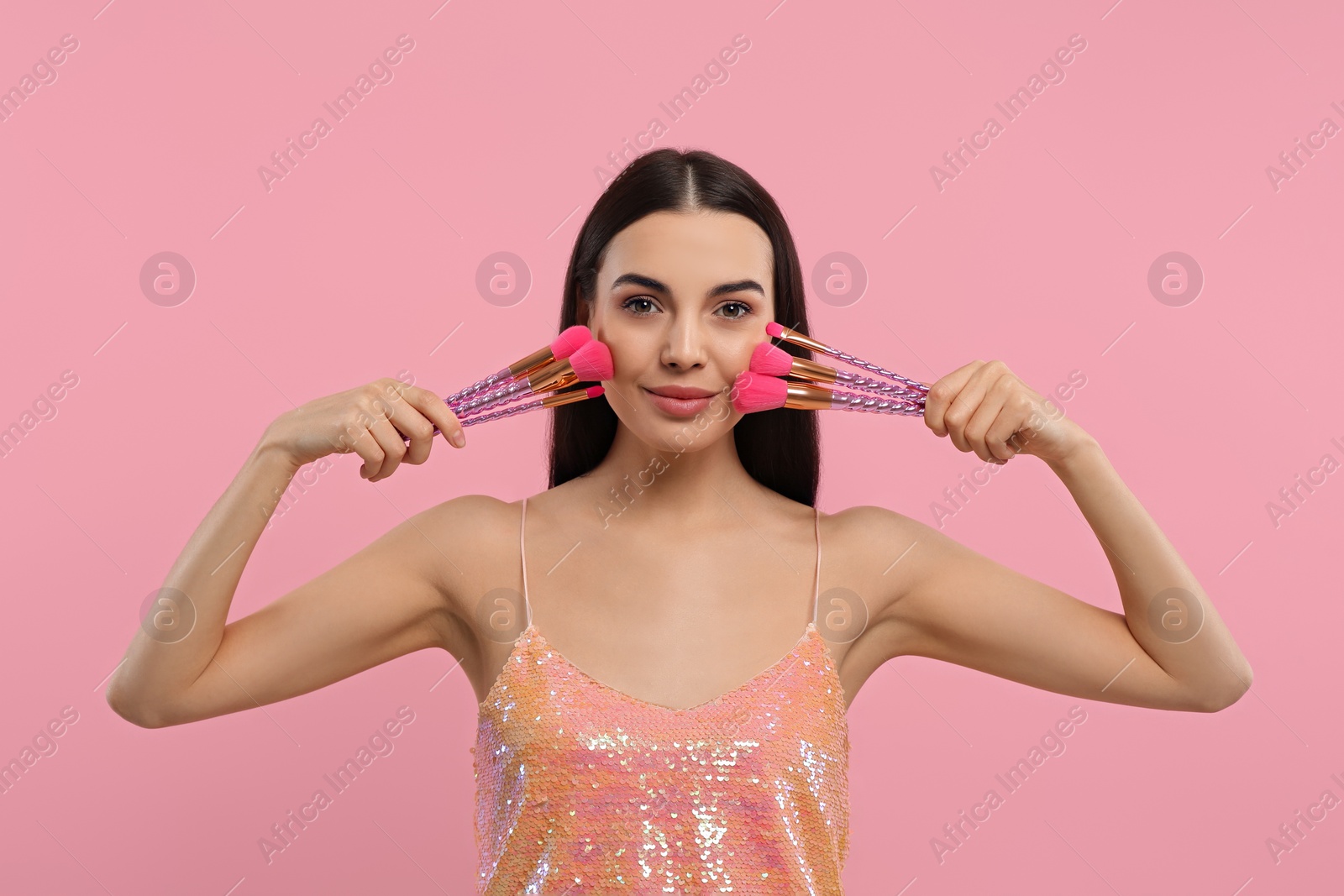 Photo of Beautiful woman with different makeup brushes on pink background