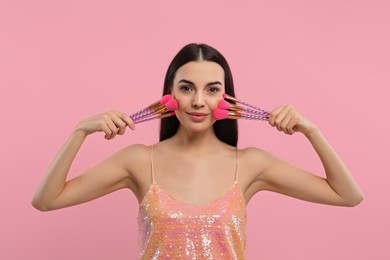 Photo of Beautiful woman with different makeup brushes on pink background