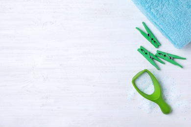 Photo of Flat lay composition with clothespins, towel and measuring scoop of laundry powder on white wooden background. Space for text