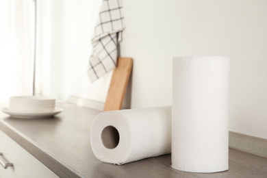 Photo of Rolls of paper towels on wooden table in kitchen