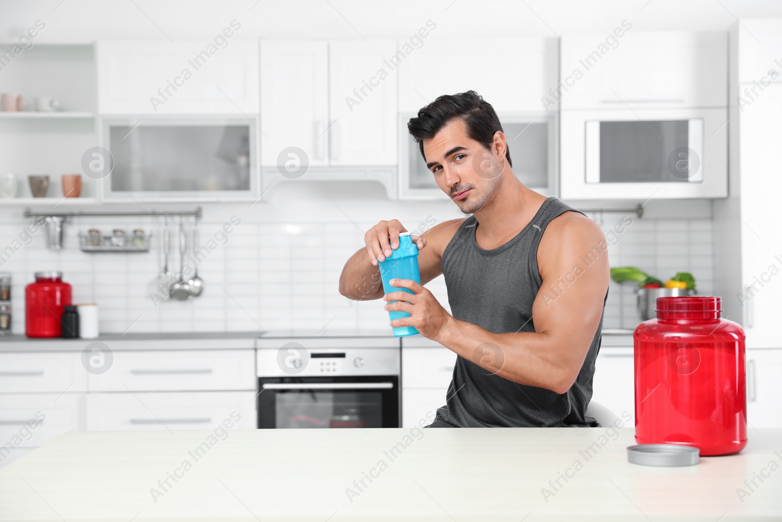 Photo of Young athletic man with protein shake powder in kitchen, space for text