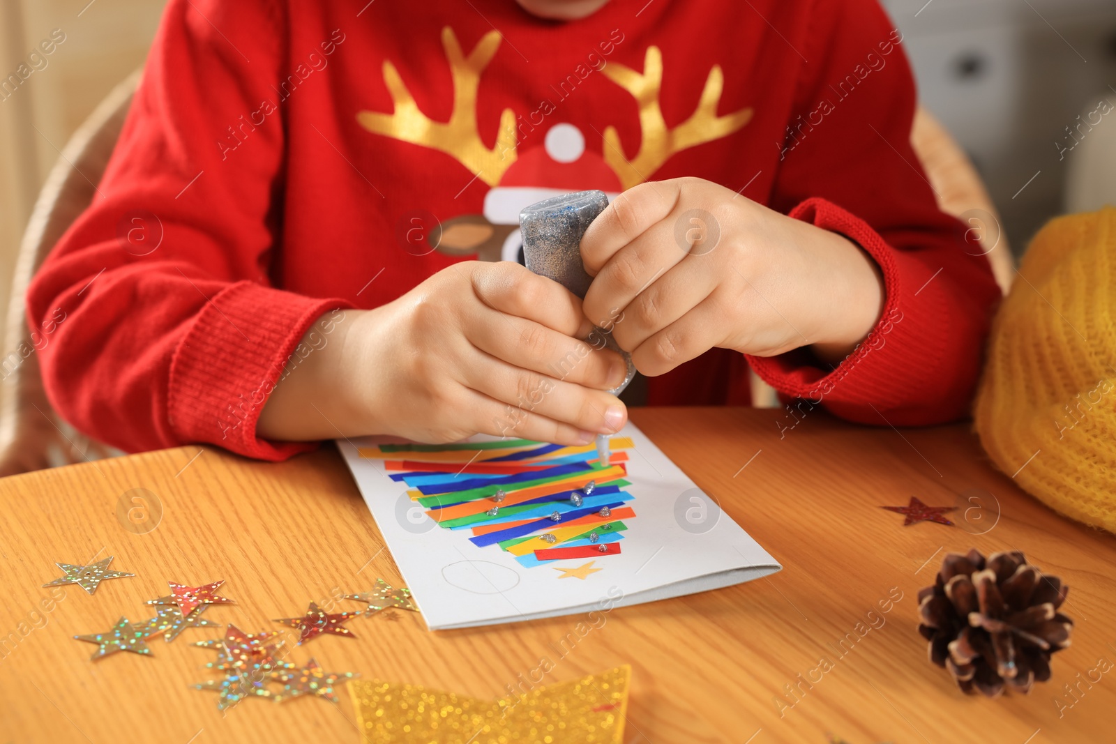 Photo of Little child making beautiful Christmas greeting card at home, closeup