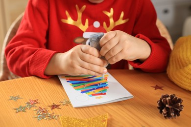 Photo of Little child making beautiful Christmas greeting card at home, closeup