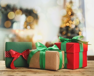 Image of Christmas gift boxes on wooden table in room, bokeh effect