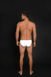 Photo of Man in underwear on black background, back view