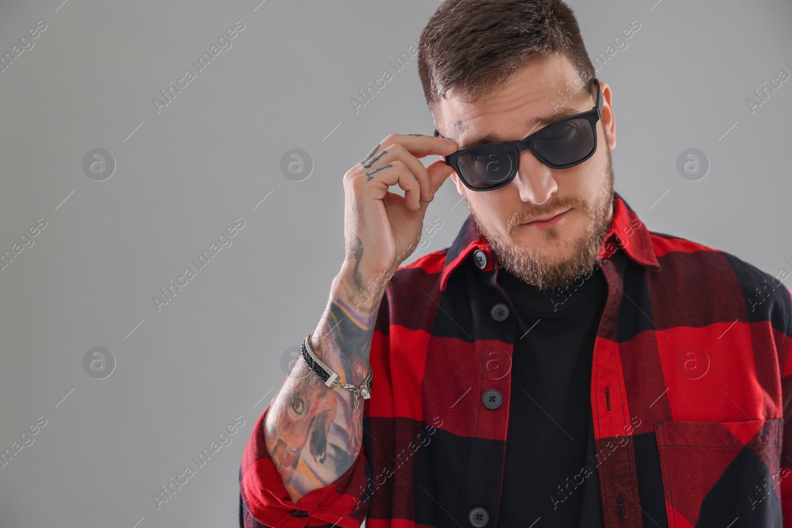 Photo of Handsome hipster man wearing stylish sunglasses on light grey background. Space for text