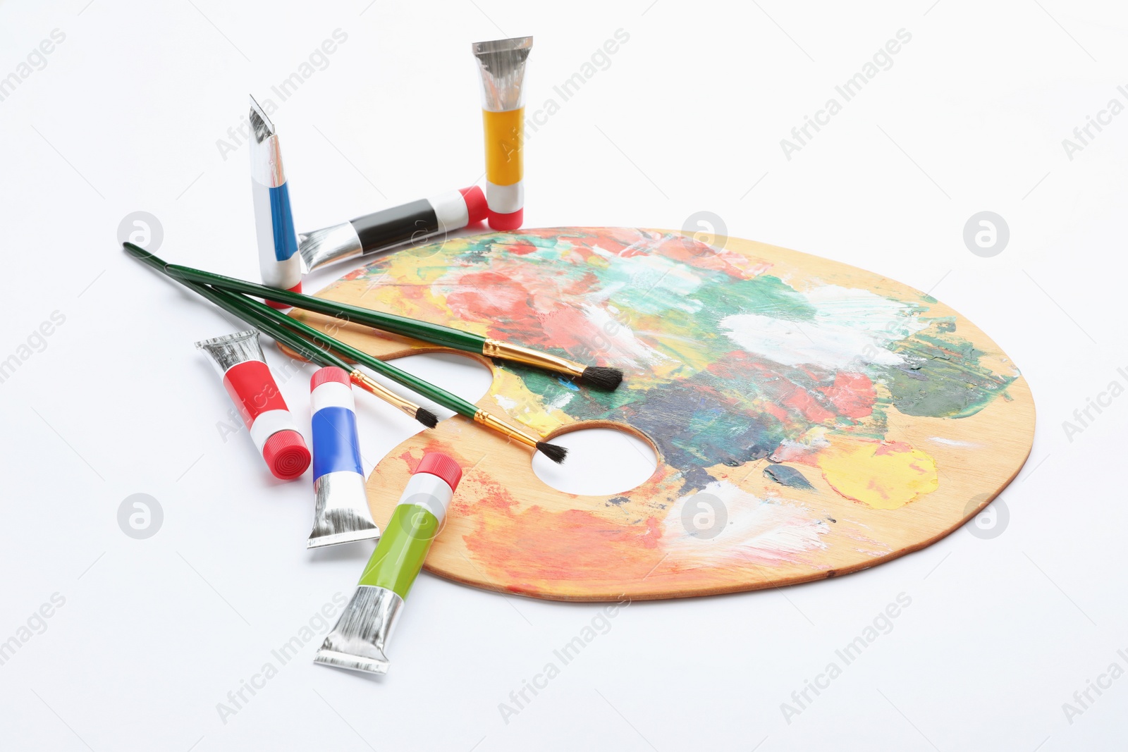 Photo of Wooden palette with brushes and acrylic paints on white background. Artistic equipment for children