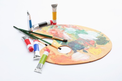 Photo of Wooden palette with brushes and acrylic paints on white background. Artistic equipment for children