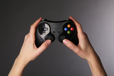 Woman using game controller on grey background, closeup
