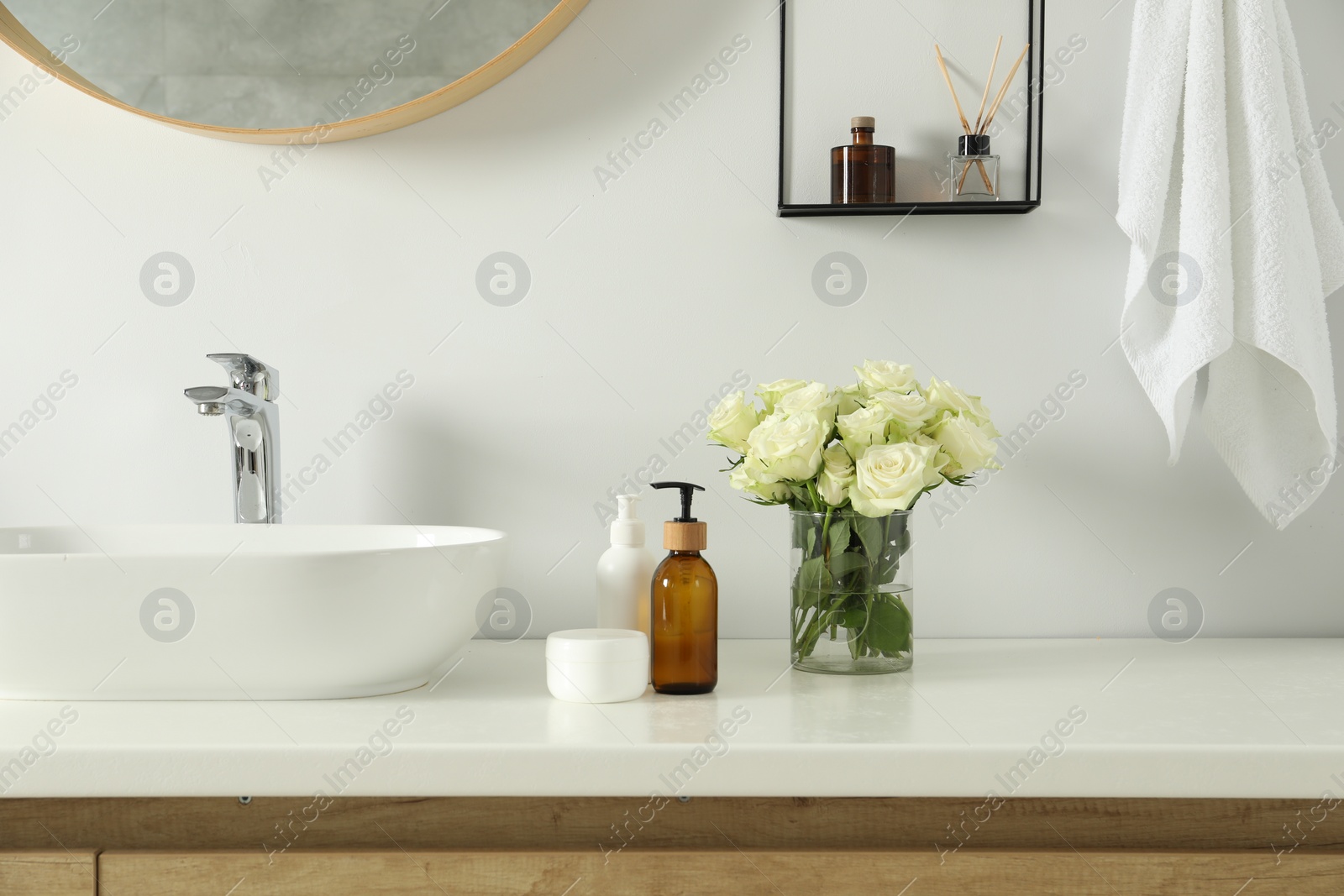 Photo of Beautiful roses and bath accessories near sink in bathroom