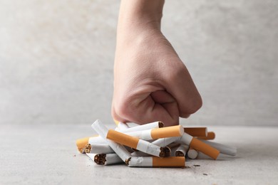 Stop smoking. Woman crushing cigarettes at grey table, closeup